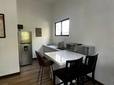 a kitchen with a counter with chairs and a refrigerator at Peaceful Apartment in Tamarindo, 50m to the Beach - Sofia Apartments in Tamarindo