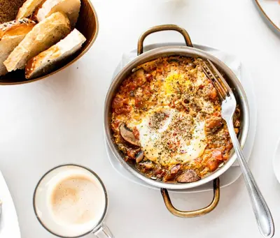 a pan of food with an egg in it next to a bowl of bread at Peaceful Apartment in Tamarindo, 50m to the Beach - Sofia Apartments in Tamarindo