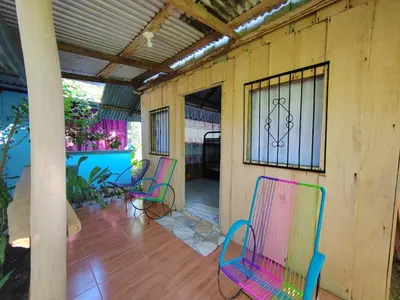 a porch with colorful chairs on a house at Los Paniquines Ecolodge in Drake