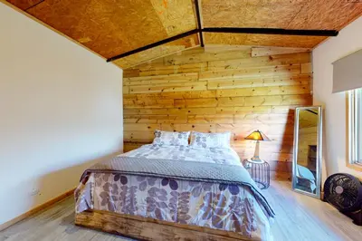 a bed in a room with a wooden wall at Finca de La Luna in Atenas