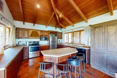 a kitchen with wooden cabinets and a island with bar stools at Finca de La Luna in Atenas