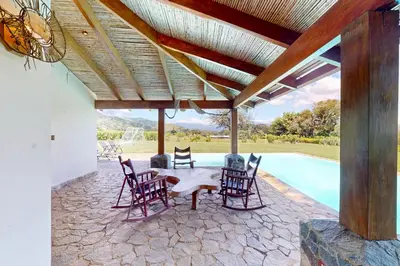 a patio with chairs and a table next to a pool at Finca de La Luna in Atenas