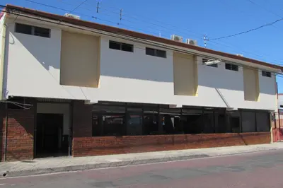 a large white building with windows on a street at Hotel La Siesta in Liberia
