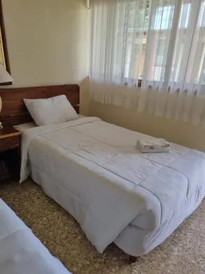 a bedroom with a large white bed and a window at Hotel La Siesta in Liberia