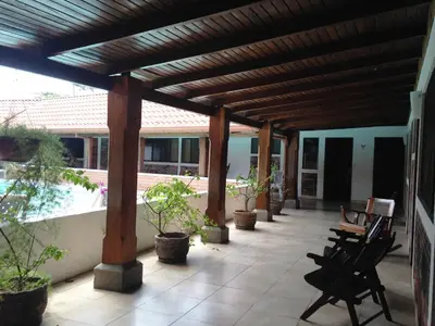 a patio with chairs and a wooden pergola at Hotel El Bramadero in Liberia