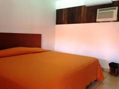 a bedroom with a bed with an orange blanket at Hotel El Bramadero in Liberia