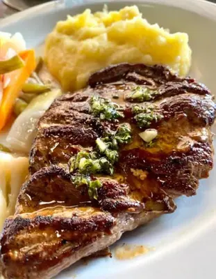 a plate of food with meat and mashed potatoes and vegetables at Hotel El Bramadero in Liberia
