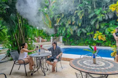 a man and woman sitting at a table with wine glasses at Dreamcatcher Hotel - Live the Dream of Santa Teresa in Santa Teresa Beach