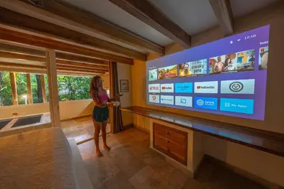 a woman standing in a room with a large screen television at Dreamcatcher Hotel - Live the Dream of Santa Teresa in Santa Teresa Beach