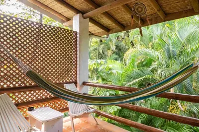 a hammock on a porch with palm trees at Dreamcatcher Hotel - Live the Dream of Santa Teresa in Santa Teresa Beach