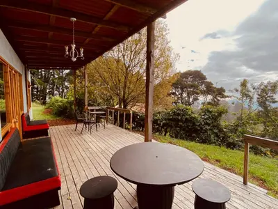 a patio with a table and chairs on a porch at Casa Monte Armadillo in Poás