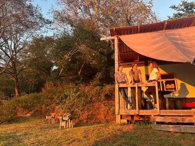 three women sitting on the porch of a tree house at Casa Monte Armadillo in Poás