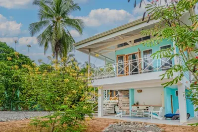 a house on the beach with a palm tree at Casa Choucoune in Parrita