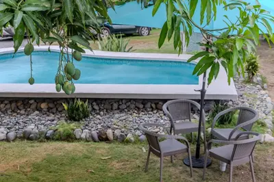 a swimming pool with two chairs and a table at Casa Choucoune in Parrita