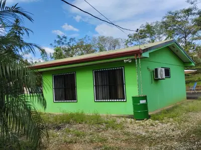 a green house with a trash can in front of it at House in Cuajiniquil ,Belen de nosarita in Cuajiniquil