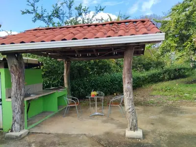 a wooden pergola with two chairs and a table at House in Cuajiniquil ,Belen de nosarita in Cuajiniquil