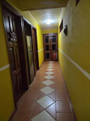 a hallway with yellow walls and a tile floor at Lodge Barka Lounge in Jabilla