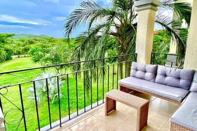a balcony with a couch and a view of a park at Palmas de Tamarindo 201D in Tamarindo
