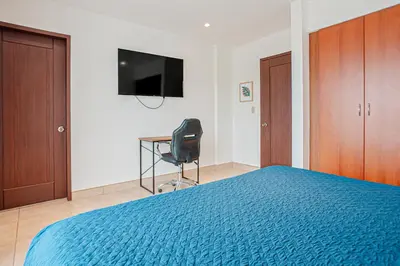 a bedroom with a blue bed and a chair and a television at Palmas de Tamarindo 201D in Tamarindo