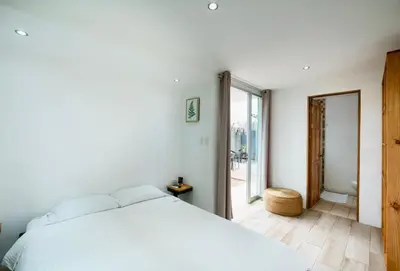 a bedroom with a white bed and a large window at Hotel Bamboo in Jacó