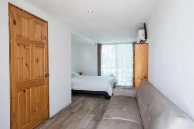 a room with a couch and a bed and a window at Hotel Bamboo in Jacó