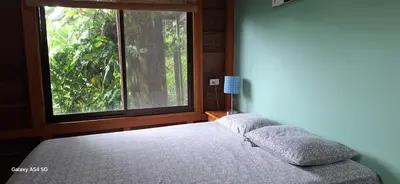 a bedroom with a bed and a large window at Cabaña Laurel in Fortuna