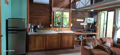 a kitchen with a refrigerator and a sink and two chairs at Cabaña Laurel in Fortuna