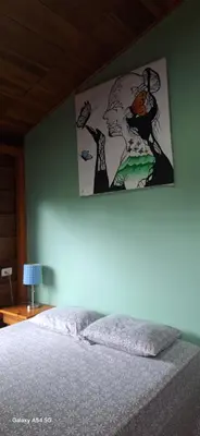 a bedroom with a painting on the wall above a bed at Cabaña Laurel in Fortuna