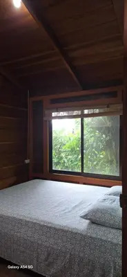a bedroom with a bed and a large window at Cabaña Laurel in Fortuna