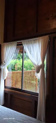 a bedroom with a window with a view of a balcony at Cabaña Laurel in Fortuna