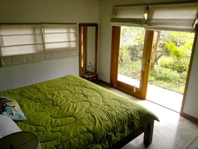 a bedroom with a green bed and two windows at Casa Amanecer Bed & Breakfast in San Ramón