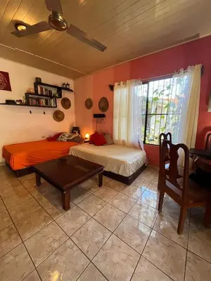 a bedroom with two beds and a table and a window at Surf House in Sámara