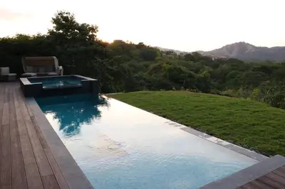 a swimming pool with a chair next to a hill at Casa Mon Coeur-Playa Del Coco Ocean View in Coco