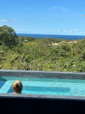 a person sitting in a swimming pool looking at the ocean at Casa Mon Coeur-Playa Del Coco Ocean View in Coco