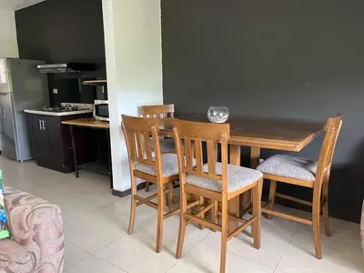 a kitchen with a wooden table and four chairs at Casa mirando a la montaña, camino al volcán in Alajuela City