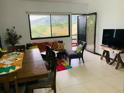 a living room with a dining table and a television at Casa mirando a la montaña, camino al volcán in Alajuela City