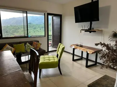a living room with a couch and a table and a television at Casa mirando a la montaña, camino al volcán in Alajuela City