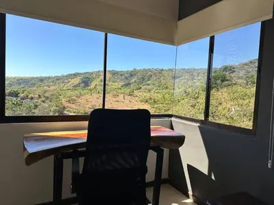 a chair sitting at a table in front of a window at Casa mirando a la montaña, camino al volcán in Alajuela City