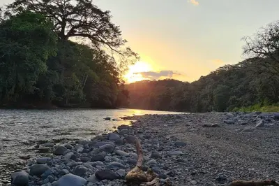 a river with a rocky shore with the sun setting at Casa de campo rodeada de naturaleza in San Francisco
