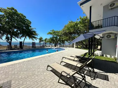 two chairs and an umbrella next to a swimming pool at BigWave Costa Rica in Playa Hermosa