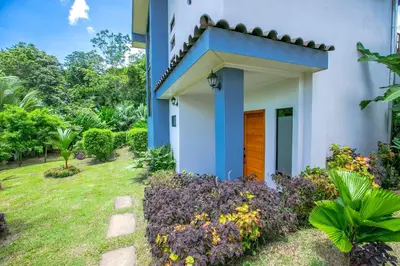 a blue and white house with a garden at Villas Sapiens Arenal in Fortuna