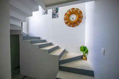 a staircase with a clock on the wall and a plant at Villas Sapiens Arenal in Fortuna