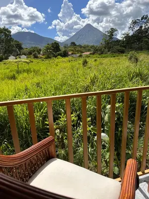 a chair on a balcony with a view of a field at Villas Sapiens Arenal in Fortuna