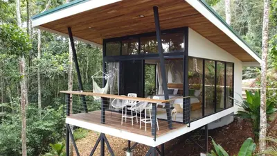 a tiny house in the woods with a porch at Pandanus Lodge & Retreats Bungalow Gingiber in Cariblanco