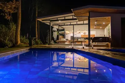 a swimming pool in front of a house at night at Pandanus Lodge & Retreats Bungalow Gingiber in Cariblanco