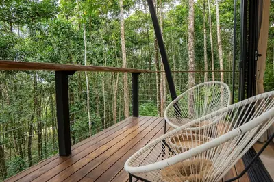 two white chairs sitting on a deck with trees at Pandanus Lodge & Retreats Bungalow Gingiber in Cariblanco