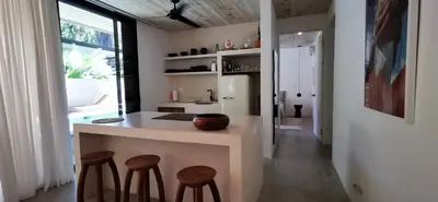 a kitchen with a island with stools and a counter at Casa Remy - Walk to the Beach and stay in a private compound! Pool, Kitchen, AC, Wi-Fi in Mal País