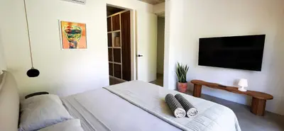 a bedroom with a bed and a flat screen tv at Casa Remy - Walk to the Beach and stay in a private compound! Pool, Kitchen, AC, Wi-Fi in Mal País