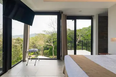 a bedroom with large windows and a bed and a chair at Vida Palace in Jacó