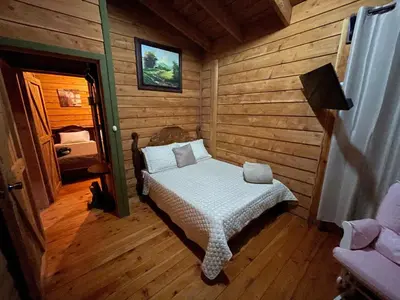 a bedroom with a bed in a log cabin at Parque Nacional Volcán Poás Cabaña Abby in Bajos Tigre